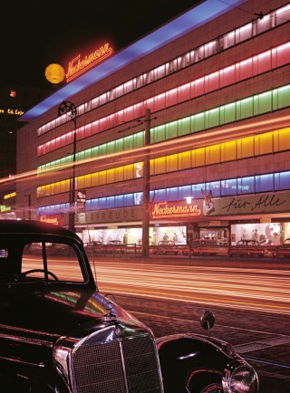 The city centers are all aglow with the bright lights of department stores like Neckermann in Frankfurt. Not quite twenty years after the lost war, the illuminated fa&ccedil;ades proudly proclaimed the affluence that had been achieved. <br /> <br /> In the foreground a Mercedes-Benz 220 Saloon, the new status symbol. The mail-order magnate and later tour operator Josef Neckermann is an icon of the "reconstruction". His slogan "Neckermann makes it possible" is the fanfare of a hitherto unknown mass prosperity.<br /> <br /> Photo (c) Josef Heinrich Darchinger, 1964