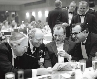 Josef Heinrich Darchinger, Wirtschaftswunder At the federal press ball. Enjoying a joke in the almanac are federal chancellor Kiesinger, FDP chairman Scheel, foreign minister Brandt and the prime minister of Rhineland-Palatinate, Helmut Kohl, who is moving unstoppably into the limelight. Bonn 1967.<br /> Photo (c) Josef Darchinger