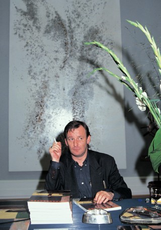Martin Kippenberger at the book launch of his first monography, in front of a caviar painting by Georg Herold, Taschen office, Cologne, 1992