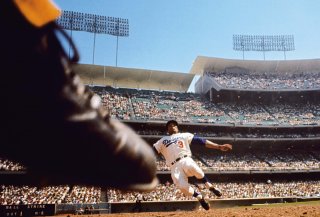 View from second base, Los Angeles Dodgers vs. Philadelphia Phillies, April 25, 1965. A camera rigged under second base captures the fielder's foot about to step on the bag as Willie Davis of the Dodgers starts to slide, all under the gaze of the crowd packing the multitiered amphitheater of Dodger Stadium. Photo (c) Neil Leifer