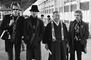 Stewart Copeland, Sting, and Andy Summers with a Japanese roshi, train station, Kyoto, 1980. (c) Andy Summers