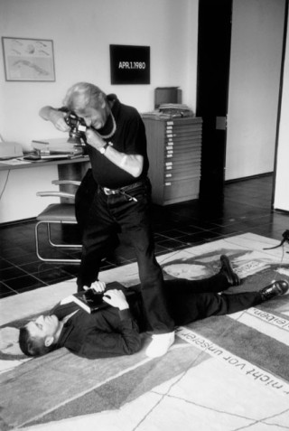 Helmut Newton shooting Albert Oehlen, lying on a carpet designed by him, in his Cologne apartment, for an advertising campaign (<em>A passion for Taschen</em>). Foto: TASCHEN, 1999